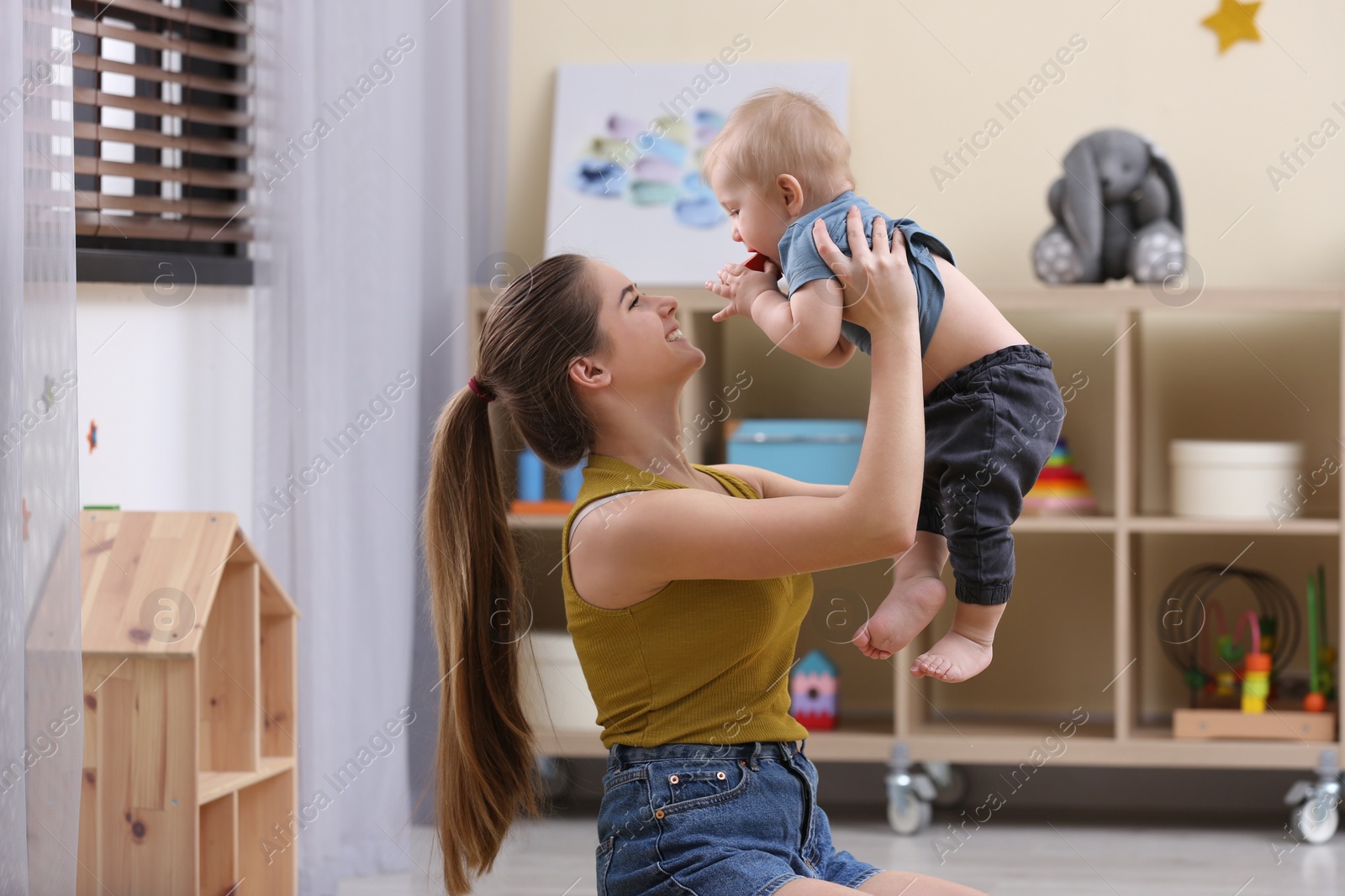 Photo of Teen nanny playing with cute little baby at home