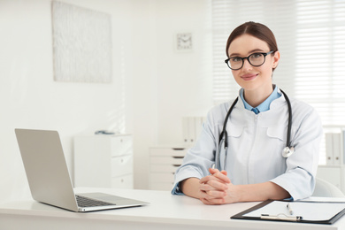 Portrait of young female doctor in white coat at workplace