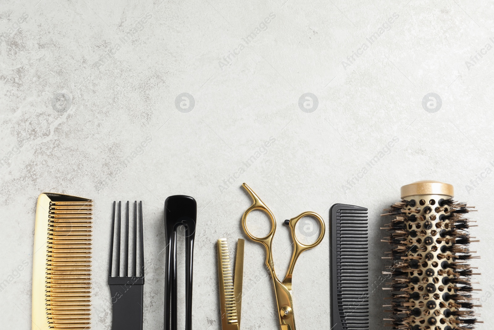 Photo of Professional hair dresser tools on grey textured background, flat lay. Space for text