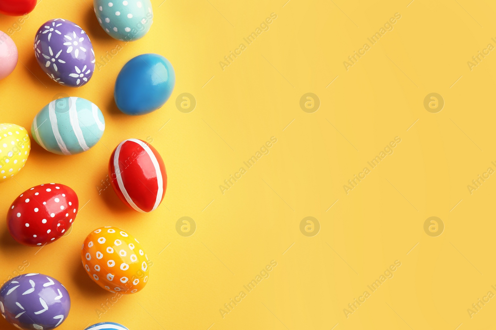 Photo of Flat lay composition of painted Easter eggs on color background, space for text