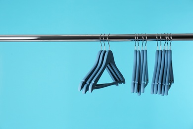 Photo of Metal rack with clothes hangers on color background, space for text