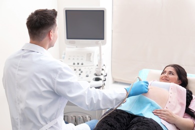 Photo of Young pregnant woman undergoing ultrasound scan in clinic