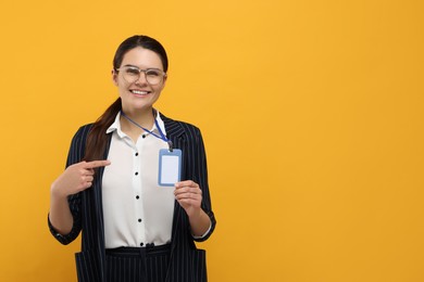 Happy woman pointing at vip pass badge on orange background. Space for text
