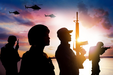 Image of Silhouettes of soldiers in uniform with assault rifles and military helicopters patrolling outdoors