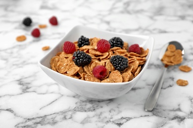 Photo of Bowl with cornflakes and berries on marble table. Whole grain cereal for breakfast