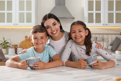 Photo of Happy mother with her children at table in kitchen. Adoption concept
