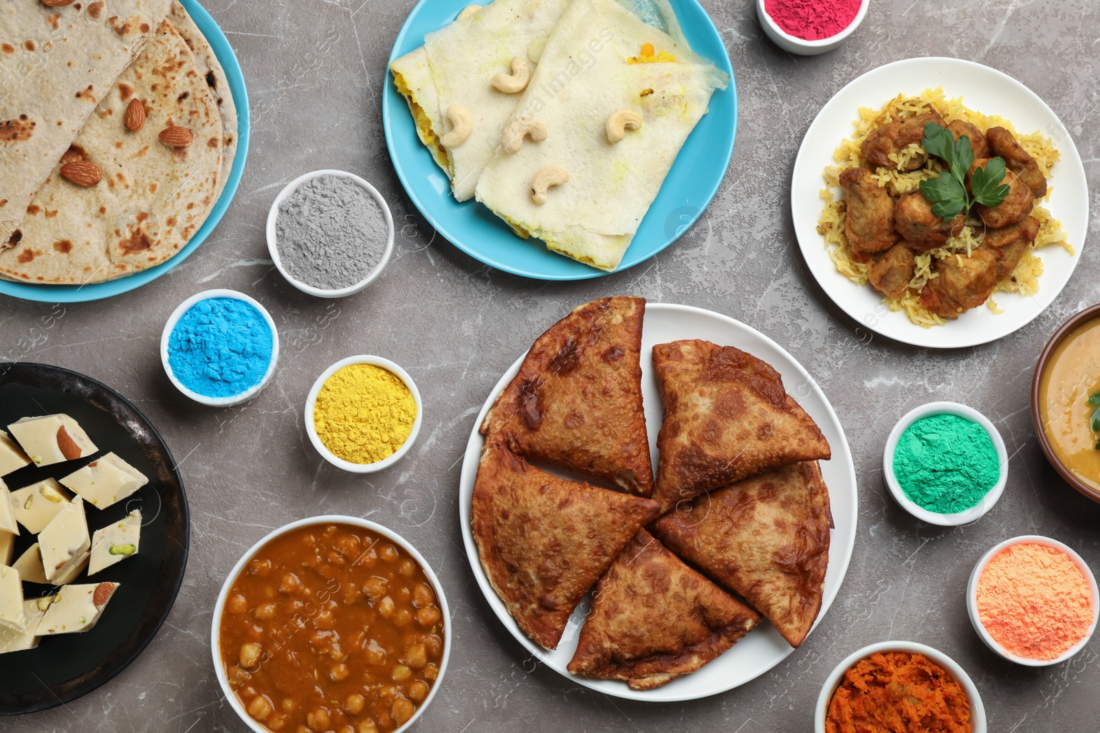 Photo of Traditional Indian food and color powders on grey table, flat lay. Holi festival celebration