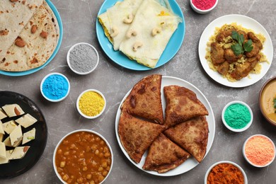 Photo of Traditional Indian food and color powders on grey table, flat lay. Holi festival celebration