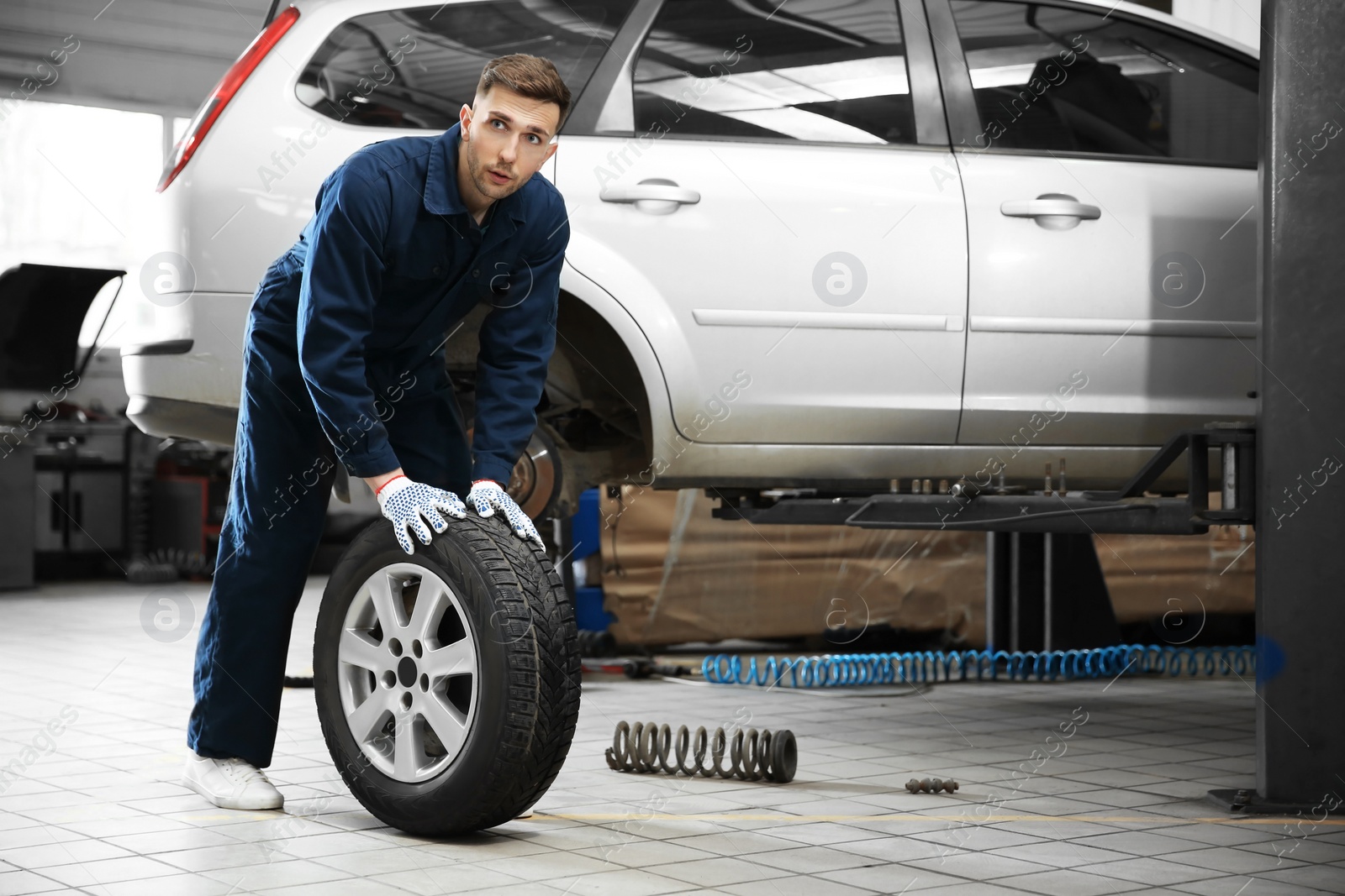 Photo of Young mechanic with car tire in service center