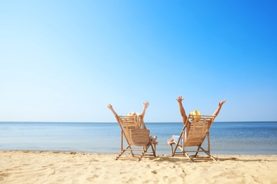 Young couple relaxing in deck chairs on beach