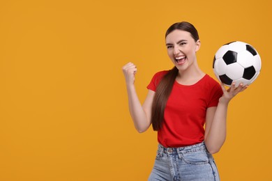 Photo of Emotional soccer fan with ball celebrating on orange background. Space for text