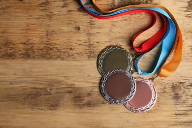 Gold, silver and bronze medals on wooden background, flat lay. Space for design