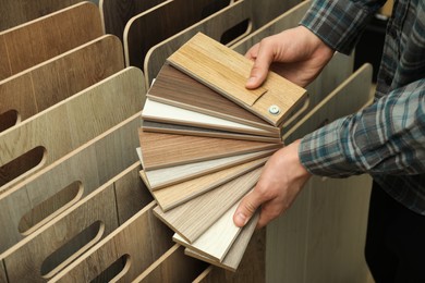 Photo of Man with samples of wooden flooring in shop, closeup