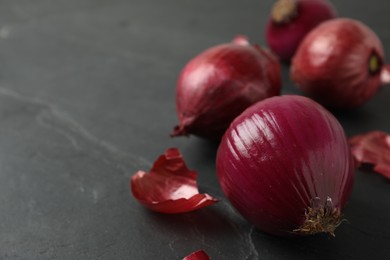 Ripe red onion bulbs on black slate table, closeup