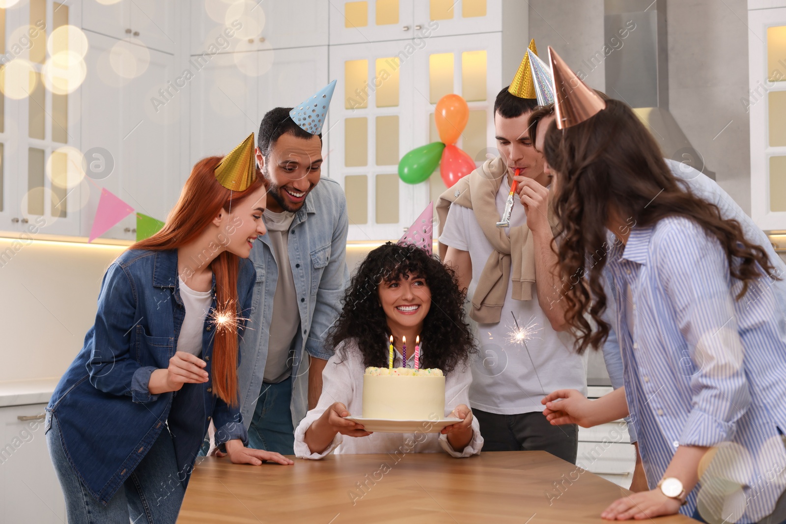 Photo of Happy friends with tasty cake celebrating birthday in kitchen