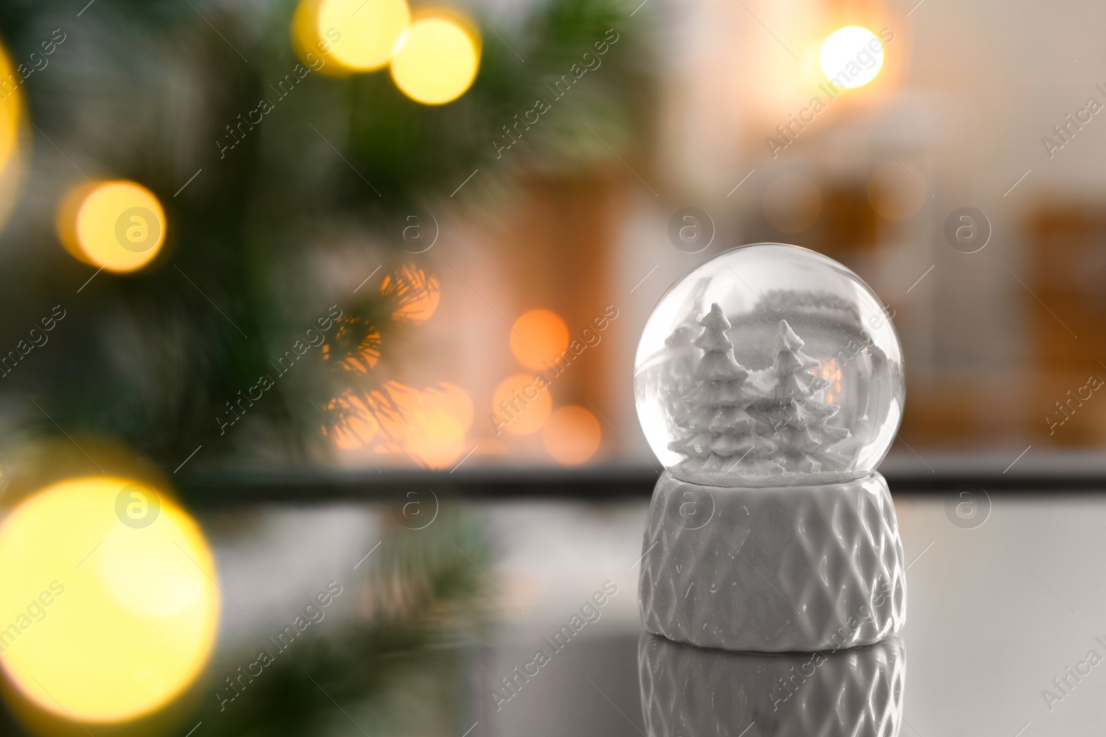 Photo of Decorative Christmas snow globe on mirror surface