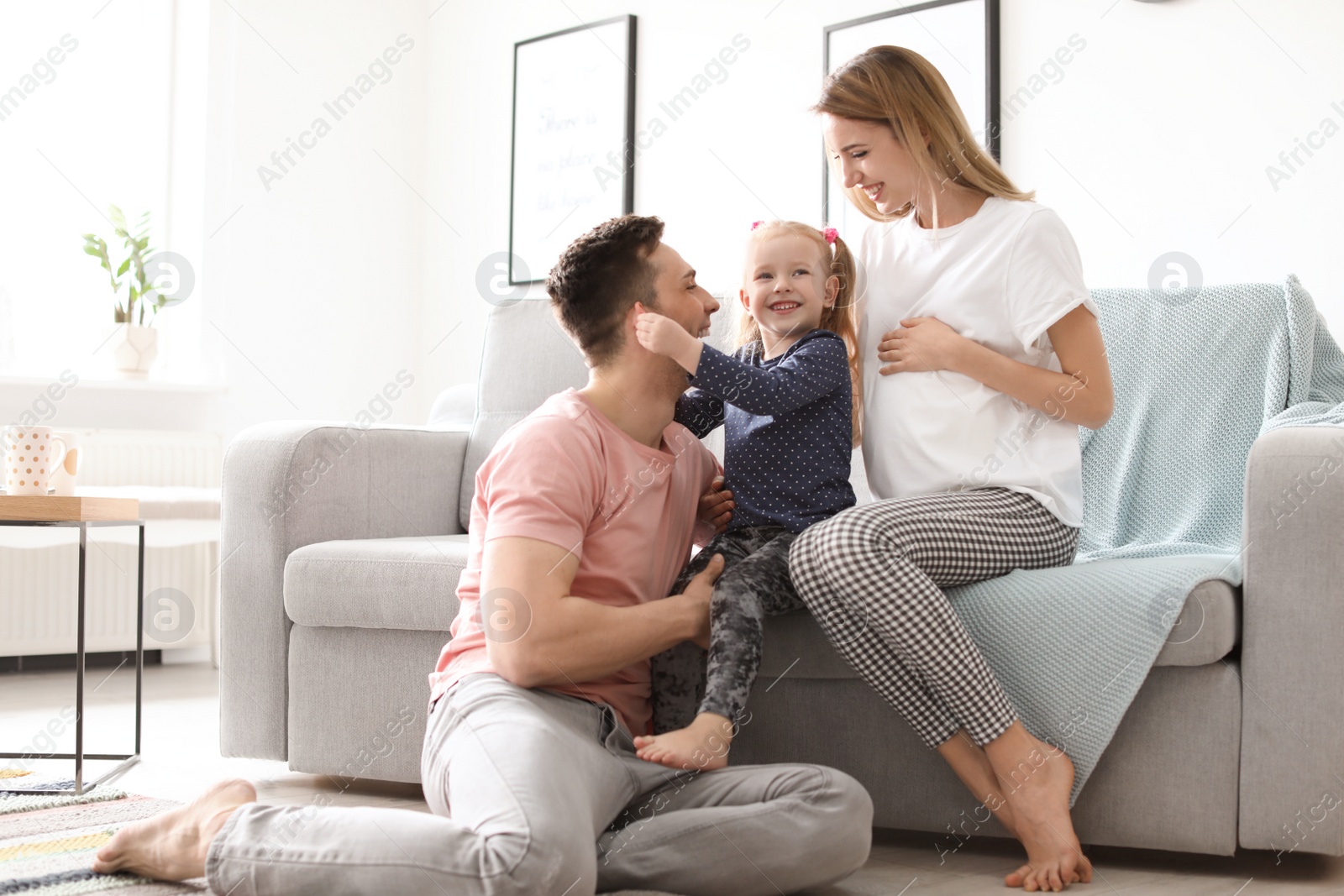 Photo of Young pregnant woman with her family at home