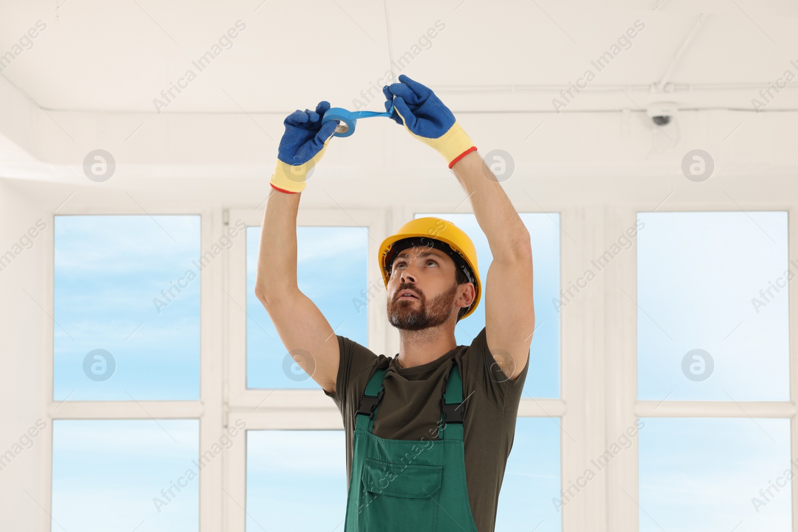 Photo of Electrician fixing wires with insulating tape indoors