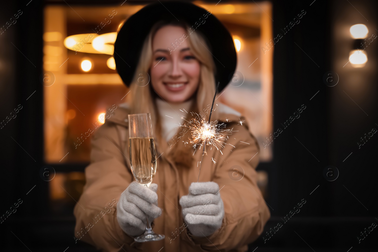 Photo of Happy young woman with sparkler and glass of champagne at winter fair