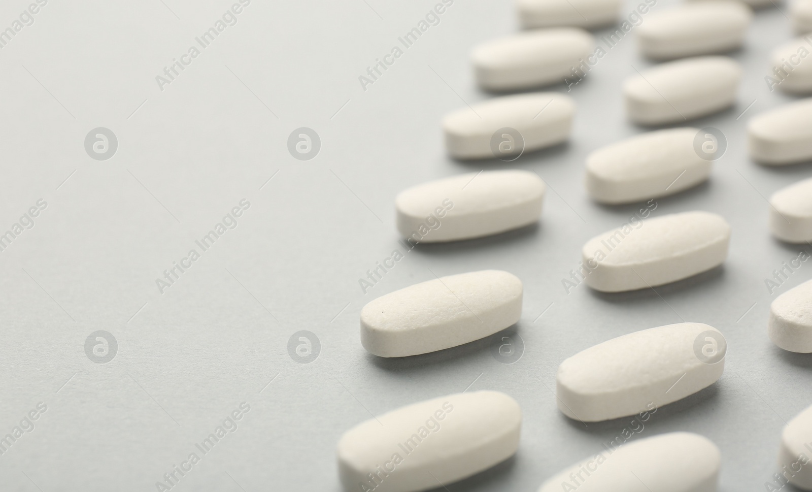 Photo of Vitamin pills on light grey background, closeup with pace for text. Health supplement