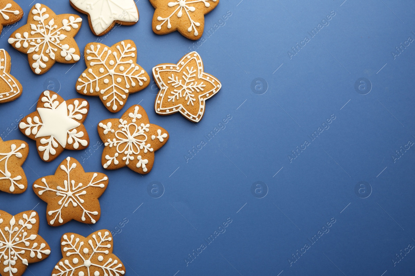 Photo of Tasty star shaped Christmas cookies with icing on blue background, flat lay. Space for text