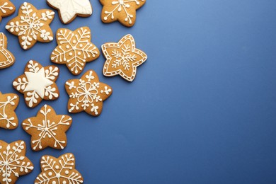 Photo of Tasty star shaped Christmas cookies with icing on blue background, flat lay. Space for text