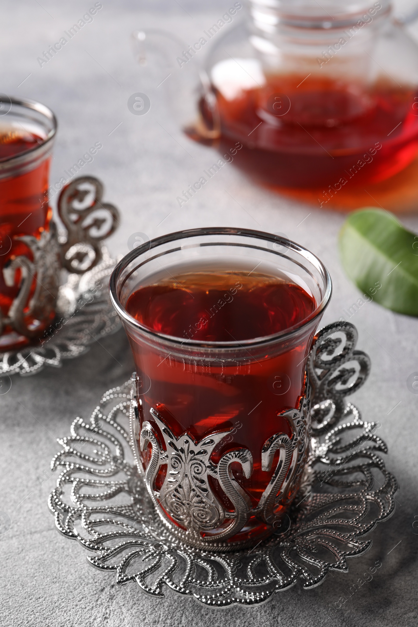 Photo of Glasses of traditional Turkish tea in vintage holders on light grey table