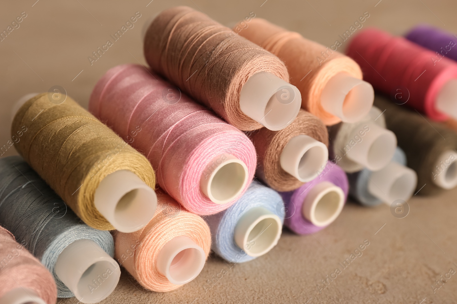 Photo of Set of color sewing threads on grey table, closeup