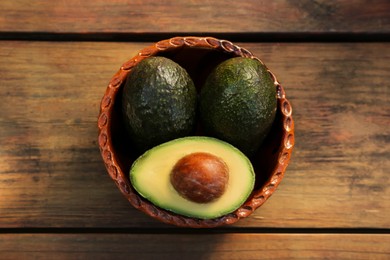 Photo of Tasty fresh avocados on wooden table, top view