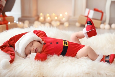 Photo of Cute baby in Christmas costume on fur rug at home