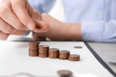 Photo of Man stacking coins at table indoors, closeup