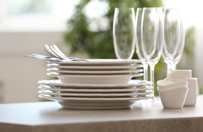 Photo of Set of clean dishware, cutlery and champagne glasses on table indoors