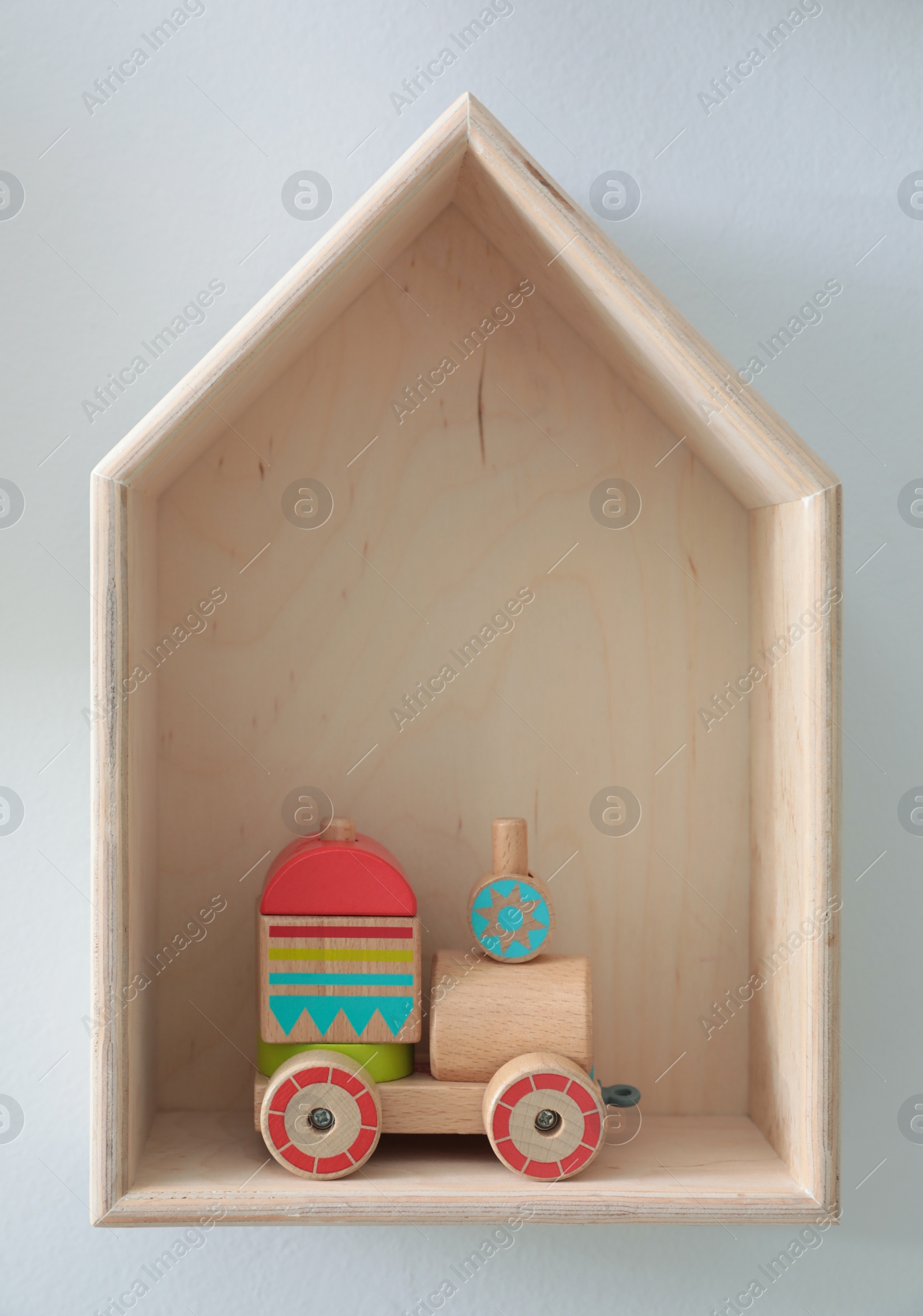 Photo of House shaped shelf with toys on white wall. Interior design