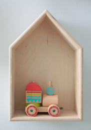 House shaped shelf with toys on white wall. Interior design