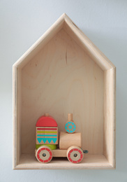 Photo of House shaped shelf with toys on white wall. Interior design