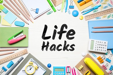 Words Life Hacks surrounded by stationery on white wooden table, flat lay