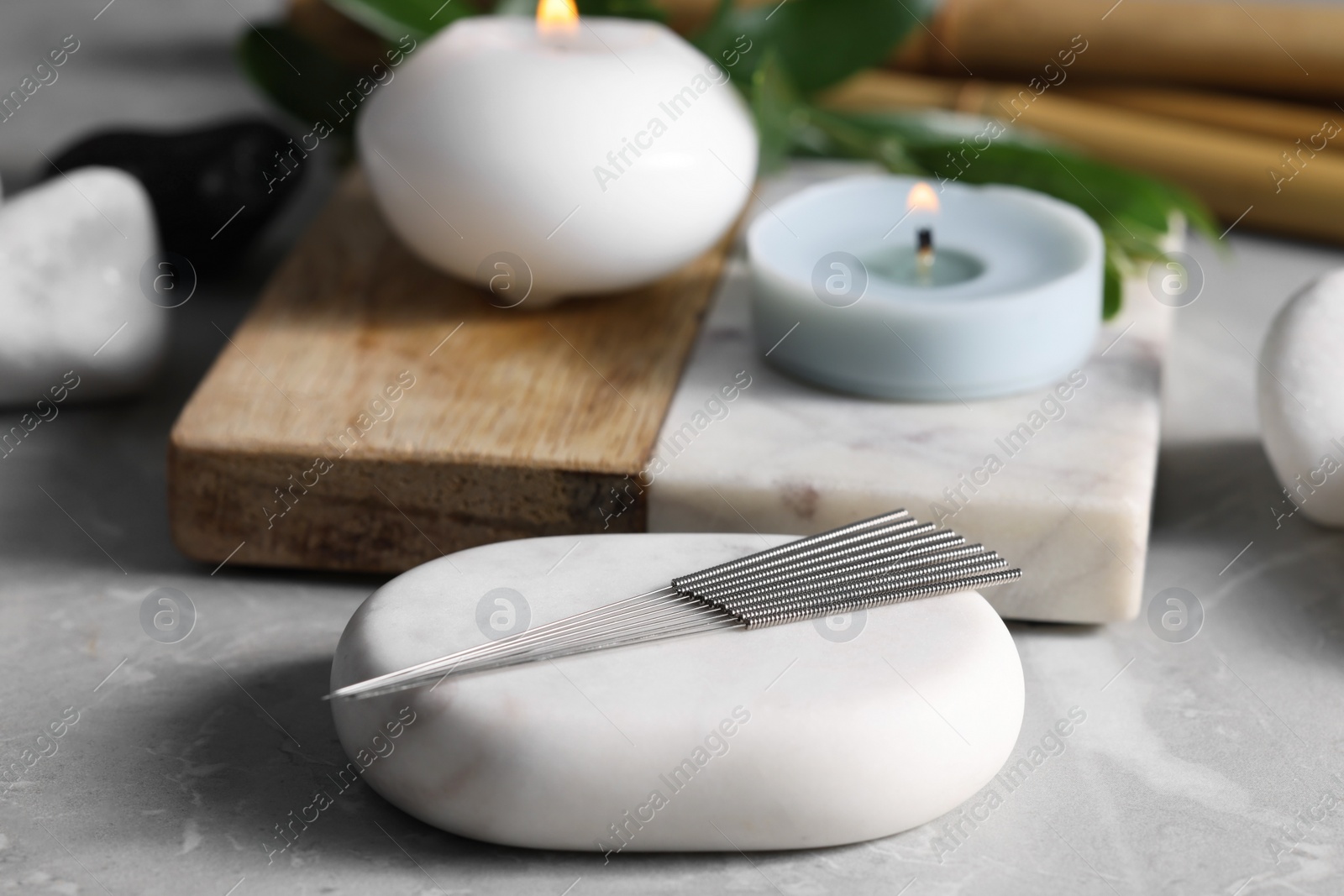 Photo of Stone with acupuncture needles on light grey marble table