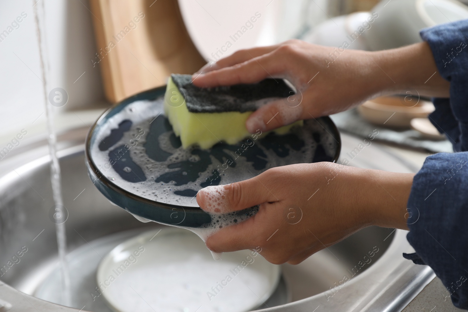 Photo of Woman washing plate in kitchen sink, closeup