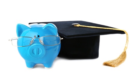 Photo of Piggy bank with glasses and graduation hat isolated on white