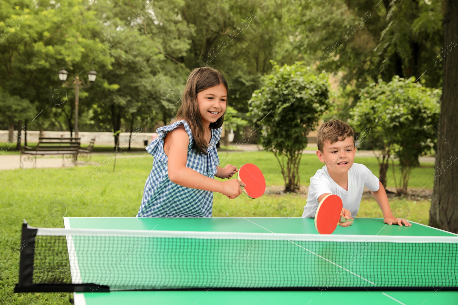 Photo of Little children playing ping pong in park