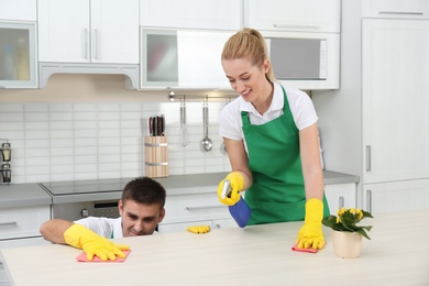 Photo of Team of janitors cleaning table in kitchen