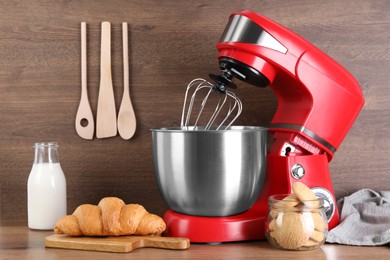 Photo of Modern red stand mixer, croissant and cookies on wooden table