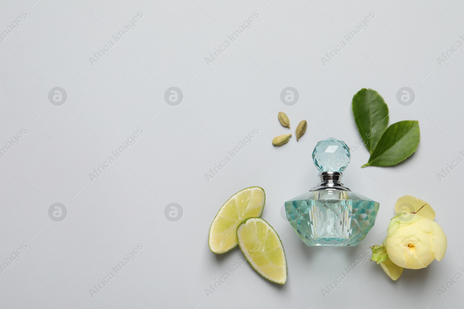 Photo of Flat lay composition with bottle of perfume, lime and  flower on light grey background. Space for text