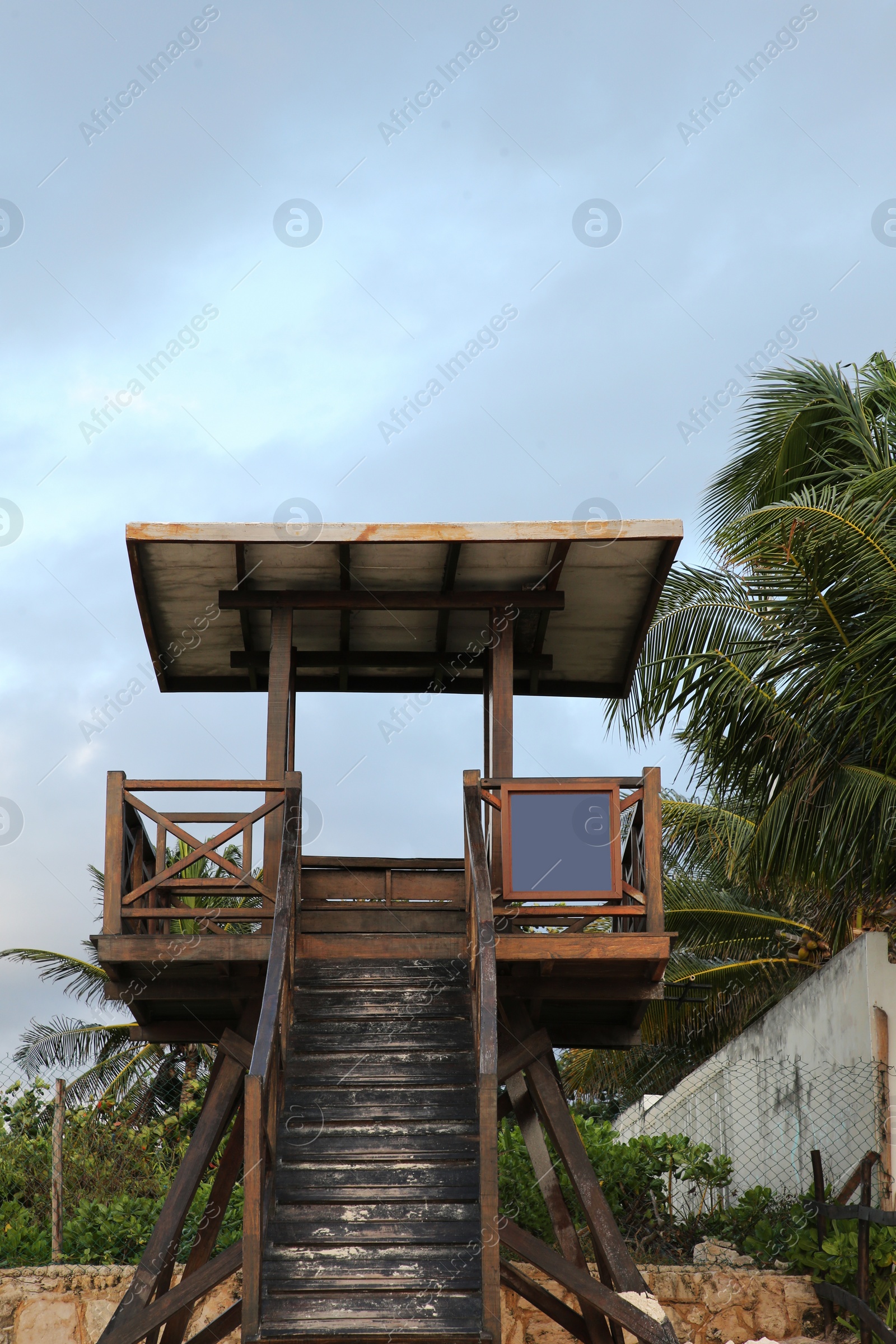 Photo of Wooden lifeguard tower near palm trees on sunny day