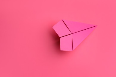 Photo of Handmade paper plane on pink background, top view. Space for text