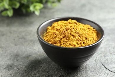 Photo of Dry curry powder in bowl on dark textured table, closeup