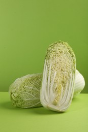 Photo of Whole and cut fresh Chinese cabbage on light green background