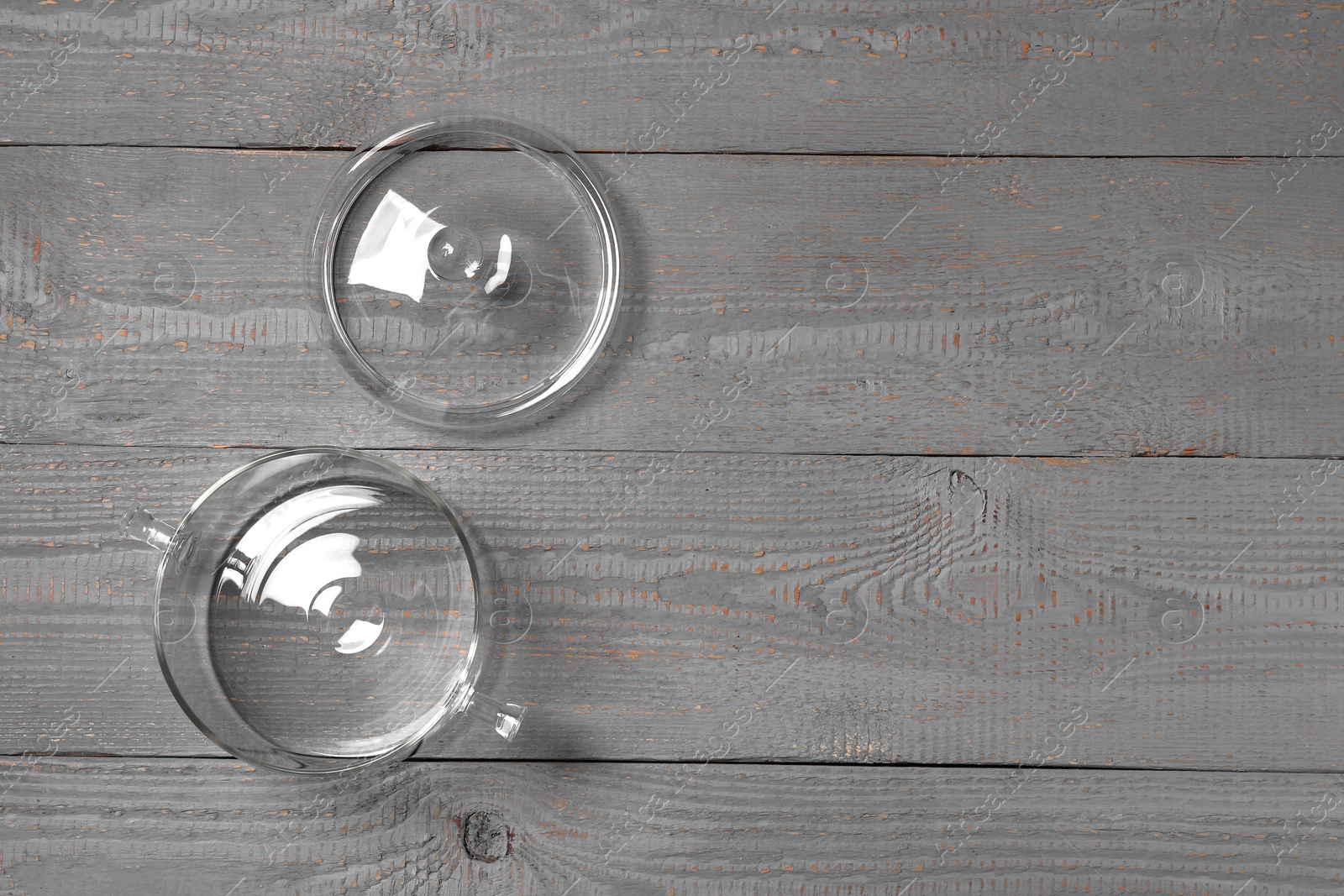 Photo of Empty glass pot and lid on grey wooden table, flat lay. Space for text