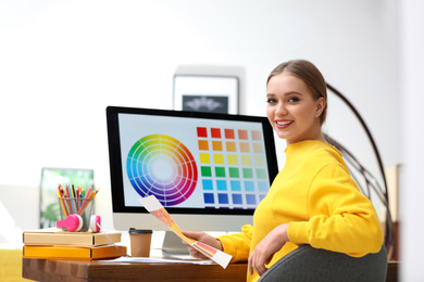 Photo of Professional designer with color palettes at workplace in office