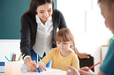 Photo of Female teacher helping girl with her task in classroom at school